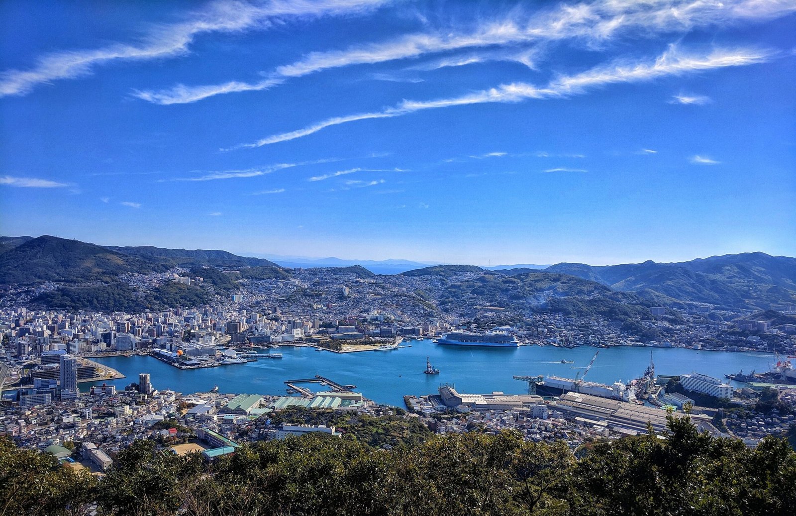 Daytime view from Mount Inasayama overlooking Nagasaki City, showing the harbor, mountains, and coas