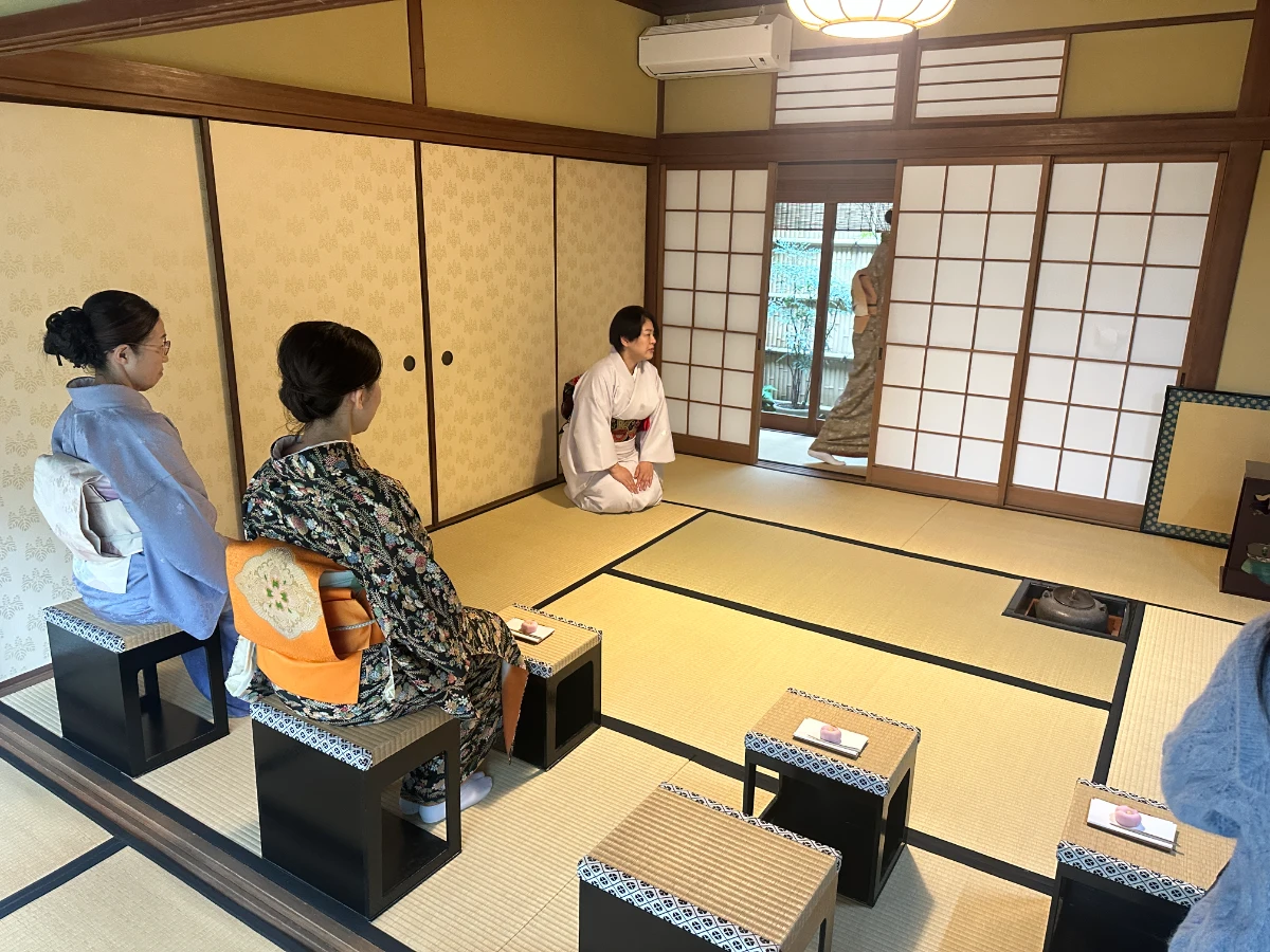 Two women wearing kimono sitting on chairs during a Japanese tea ceremony experience
